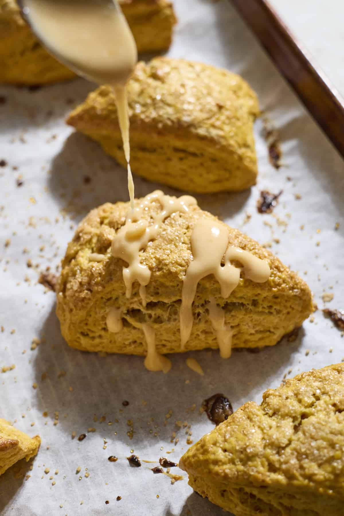 Glaze being drizzled on top of pumpkin scones.