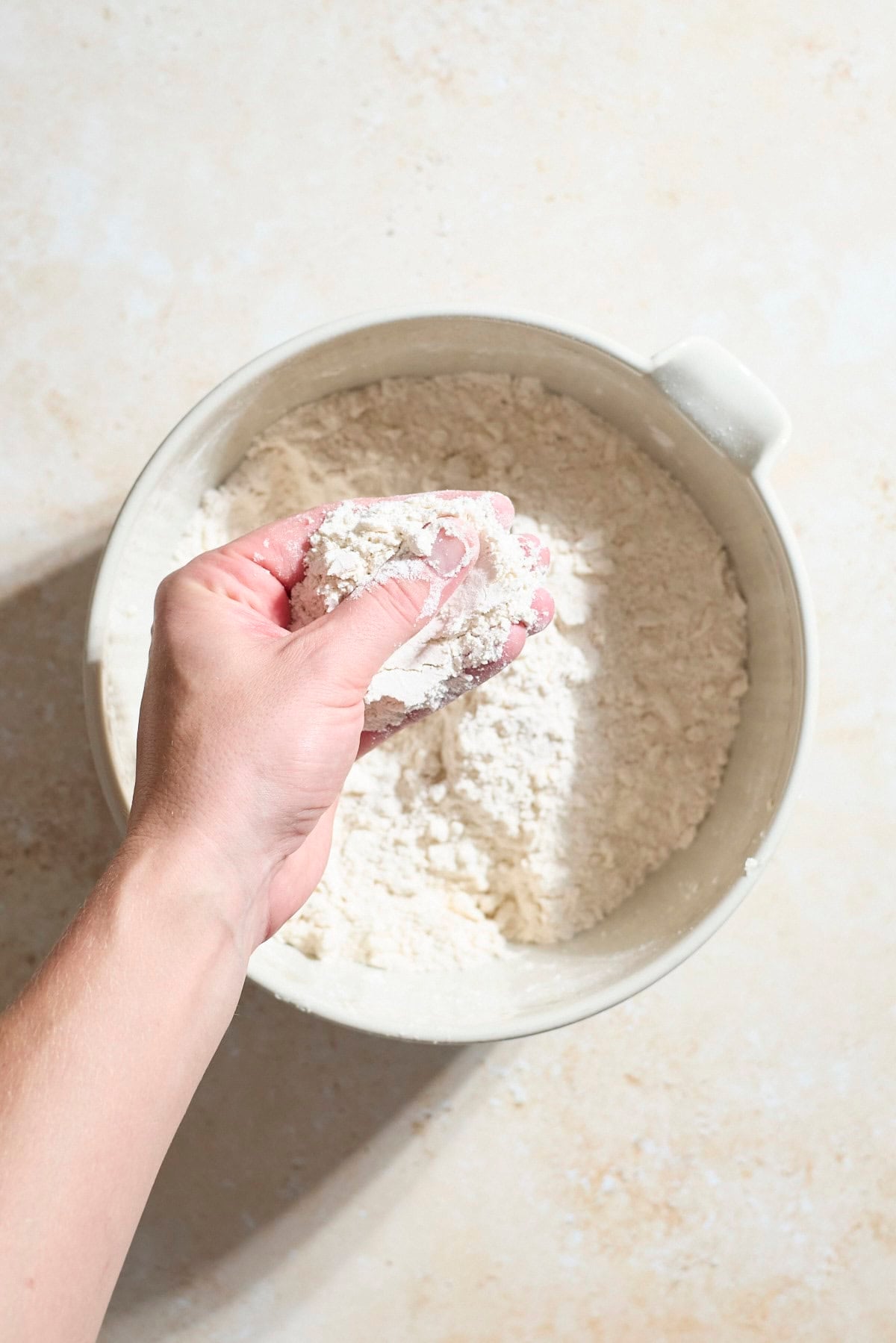 Butter and flour being pressed together between fingers.