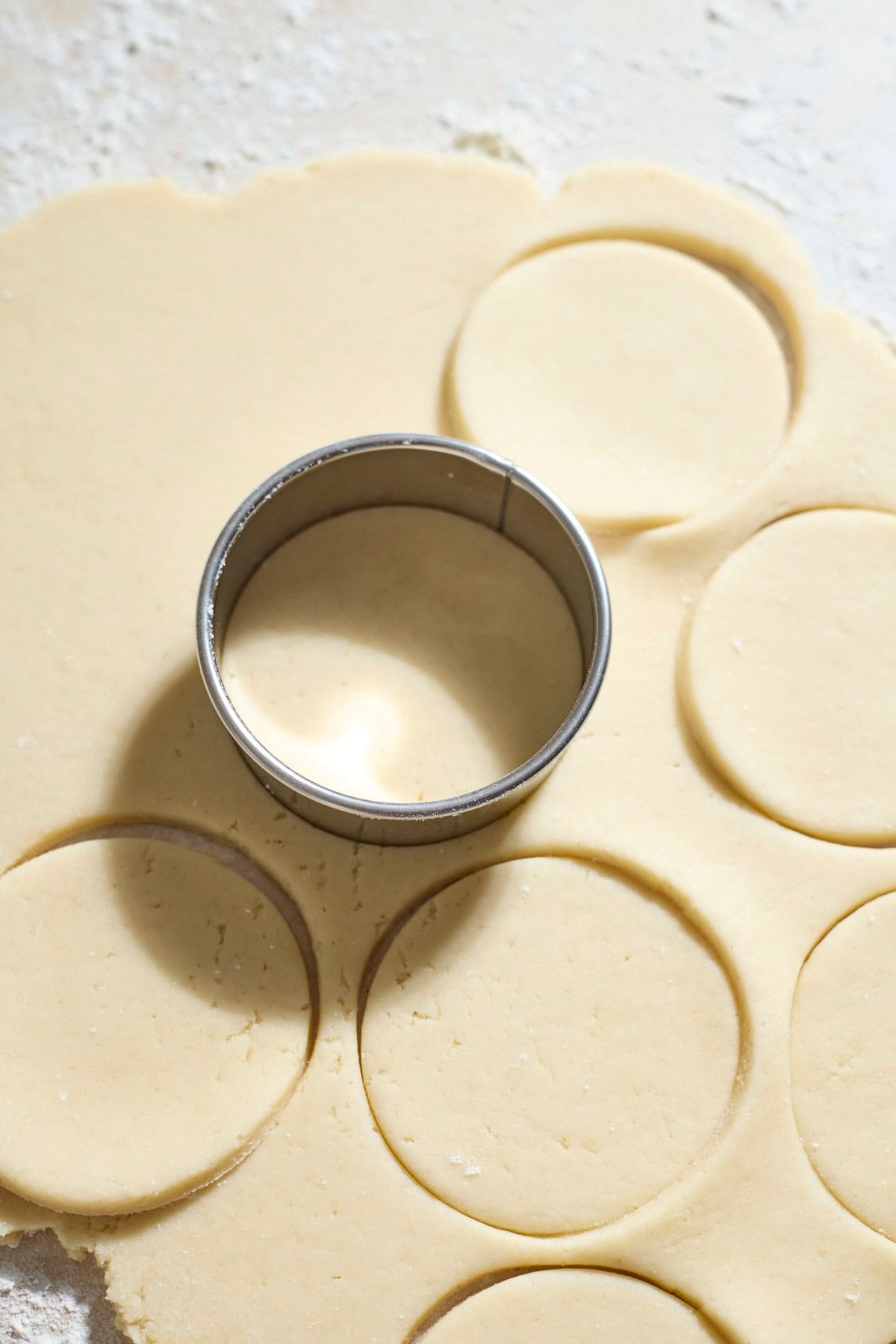 A round cookie cutter cutting circles in the dough.